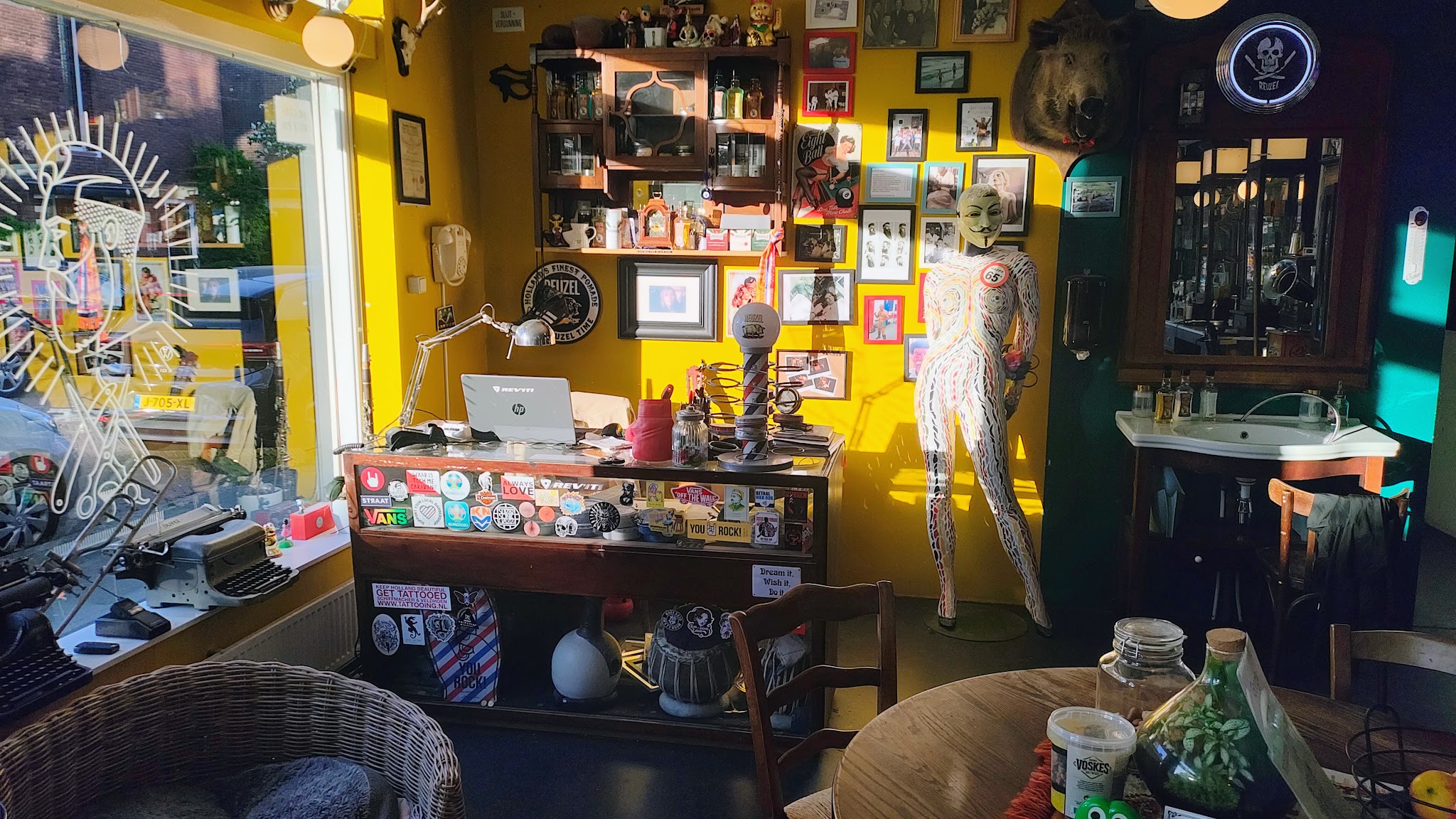 Zithoek en toonbank met gele muren, wanddecoratie en groene kozijnen
