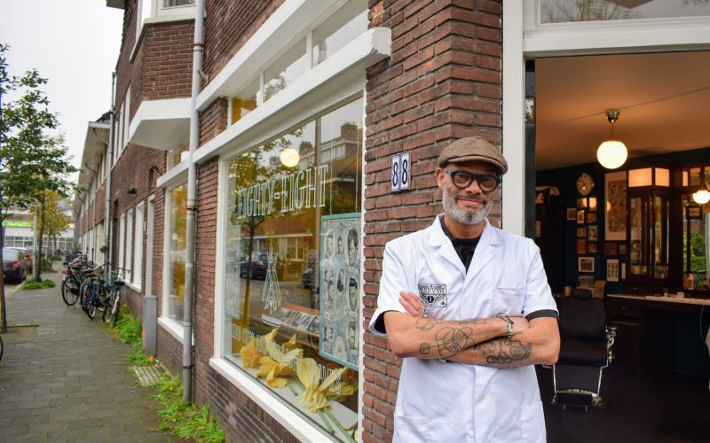 Barbier bij de ingang van Barbershop Eighty-Eight op nummer 88